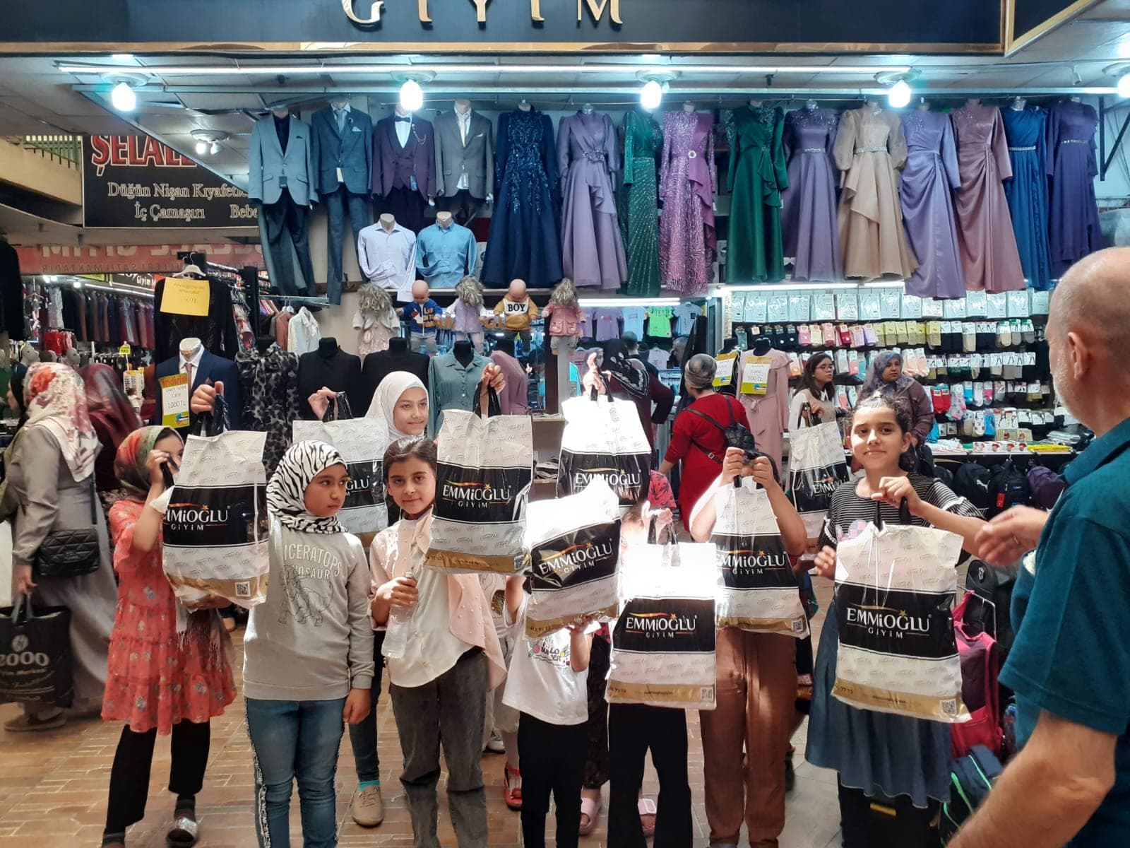 Konya'da bir giyim mağazasında yeni kıyafet poşetleriyle çocuklar
